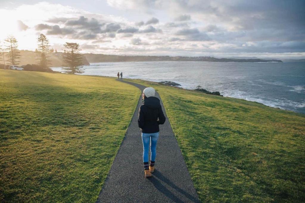 a person walking down a path near the ocean at Kaleula Upper Beach House in Kiama