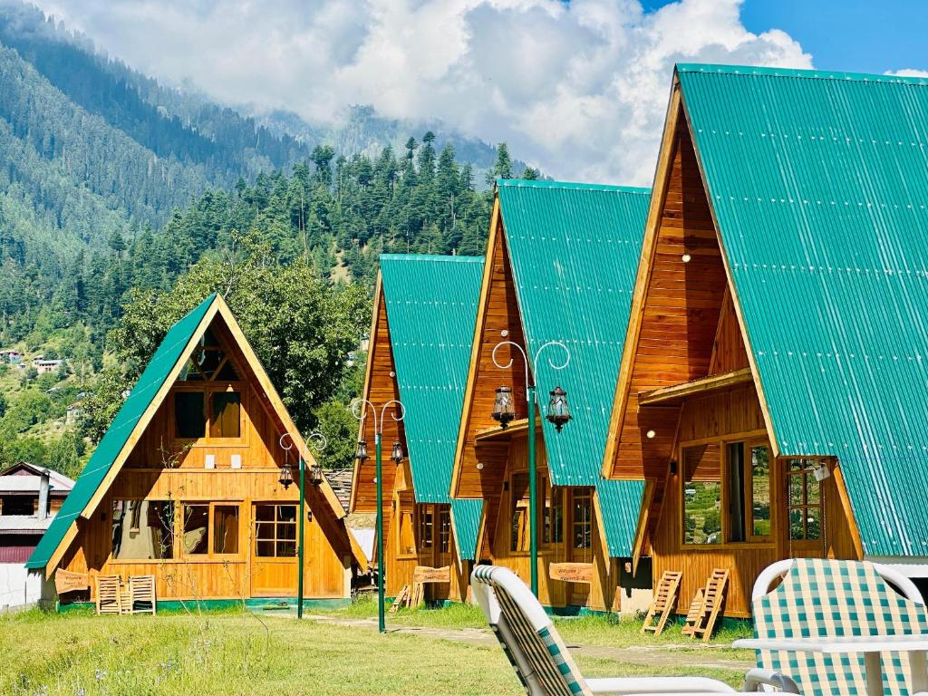 Luxury Timber Resorts and Hotels Cottages in Upper Neelum, Keran, AJK في Chak: منزل خشبي كبير مع سقف أخضر