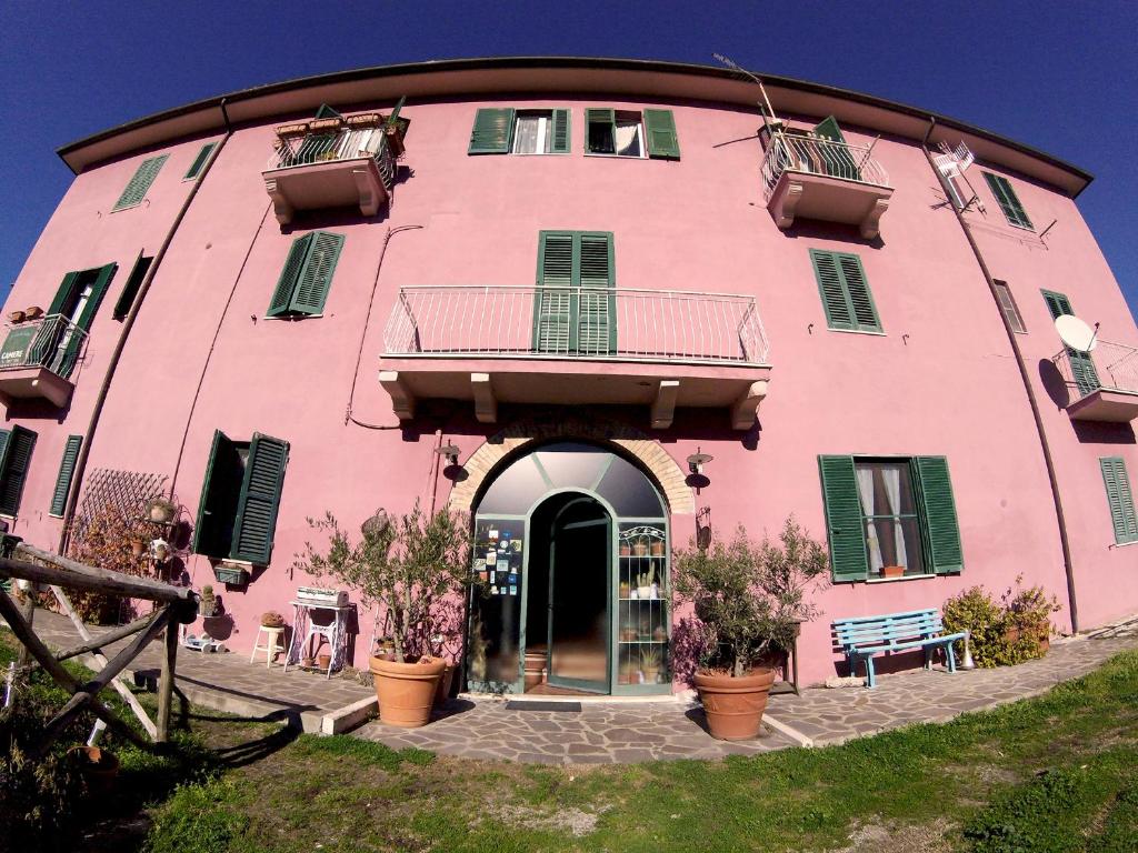 a pink building with green shutters on it at La Casa dei Carrai in Pitigliano