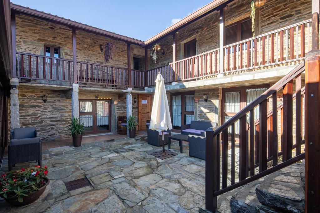 eine Terrasse mit einem Sonnenschirm und Stühlen sowie ein Gebäude in der Unterkunft O Forno do Curro -Casa da Amendoa in Boborás