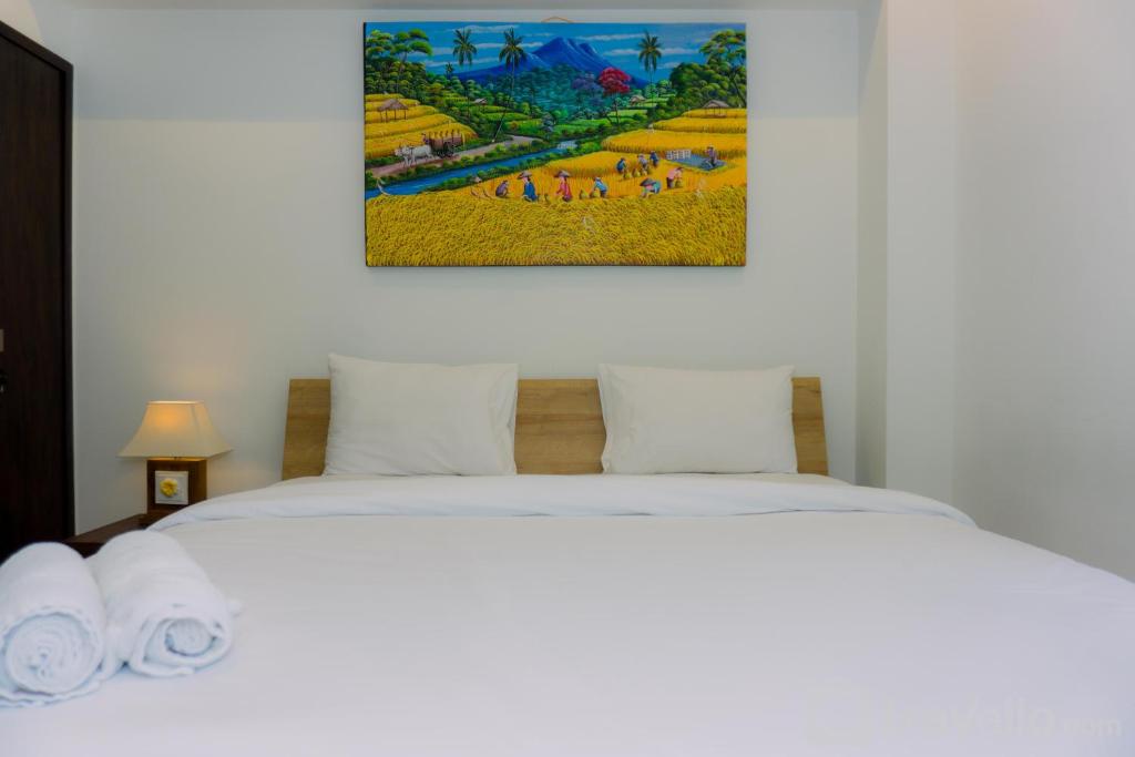 two beds in a room with a painting on the wall at A Luxury 1BR Bali Style Apartment at Branz BSD City By Travelio in Tangerang
