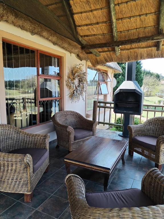 a porch with wicker chairs and a wooden table and a fireplace at lrish Mist Estate in Howick