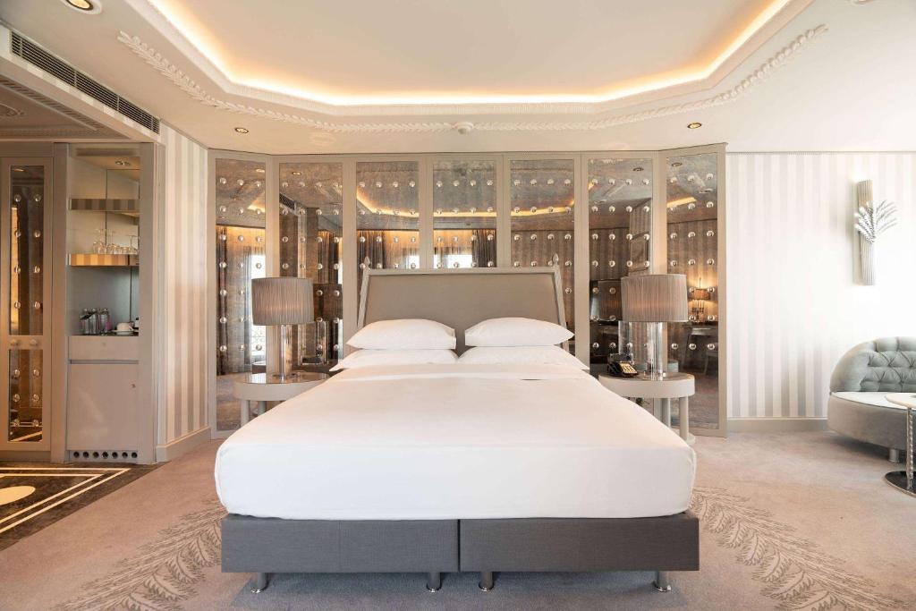 a bedroom with a large white bed and a couch at Wyndham Grand Istanbul Kalamış Marina Hotel in Istanbul