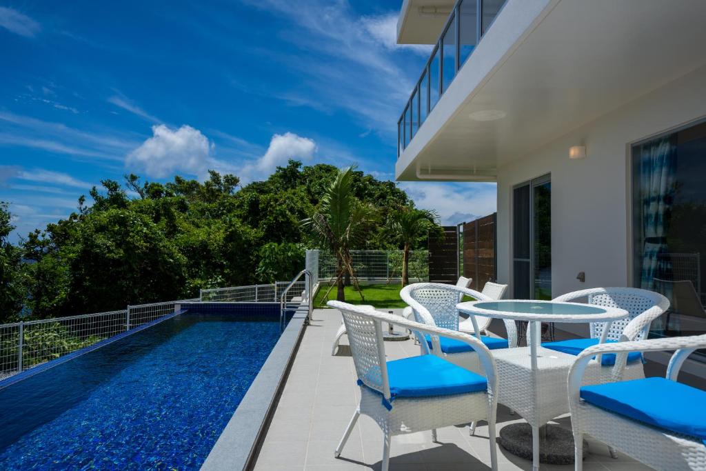a patio with a table and chairs next to a swimming pool at Pool Villa The Sweet Kouri Island in Nakijin