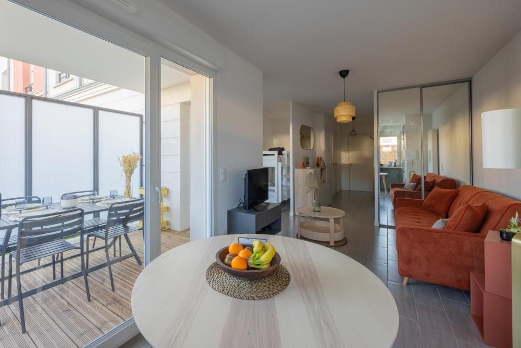a living room with a table with a bowl of fruit on it at Nid Ensoleillé - A proximité de la plage in Arcachon