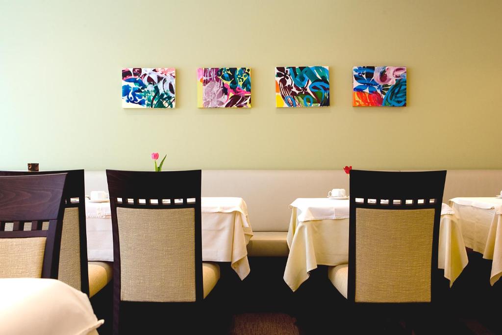 a restaurant with tables and chairs and paintings on the wall at Hotel am Jakobsmarkt in Nuremberg