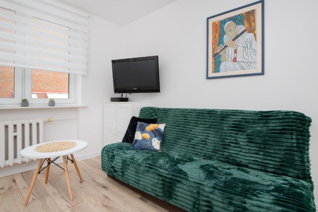 a living room with a green couch and a tv at Warzywnicza Apartment Motława River by Noclegi Renters in Gdańsk