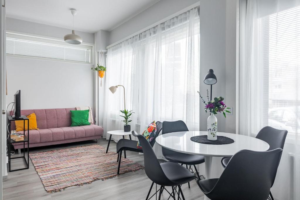 a living room with a table and chairs and a pink couch at Stylish 47m2 Studio with Private Entrance in Lahti