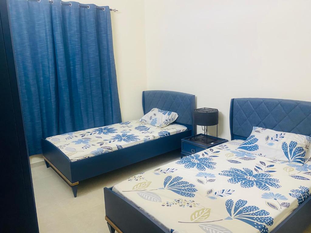 Dos camas en una habitación con cortinas azules. en Modern comforts of 311 to Dubai, en Ajman