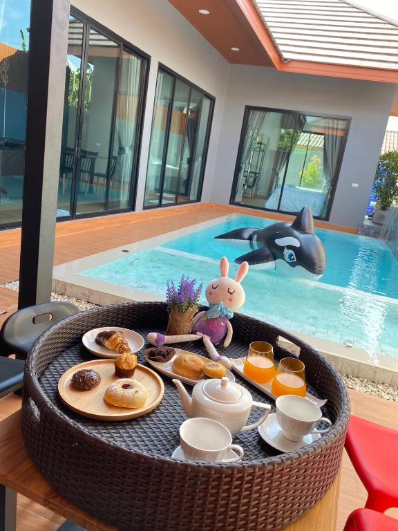 a tray of breakfast food on a table in front of a swimming pool at Bluda Poolvilla B in Hat Yai