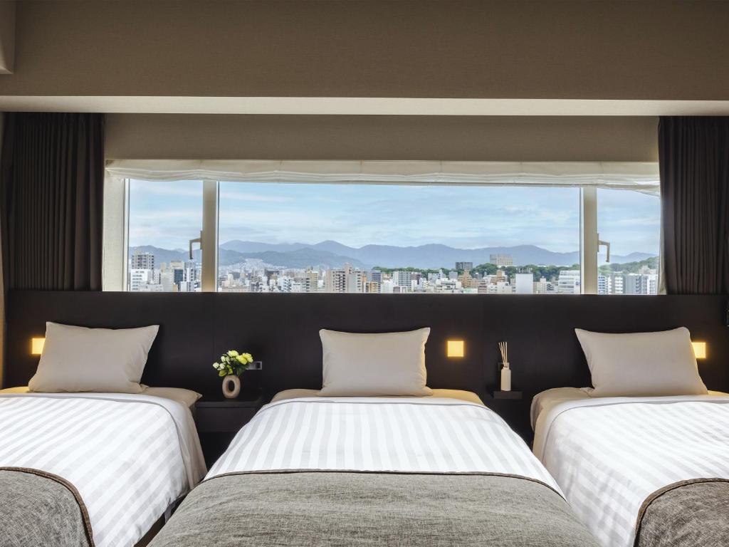 two beds in a room with a large window at Hiroshima Washington Hotel in Hiroshima