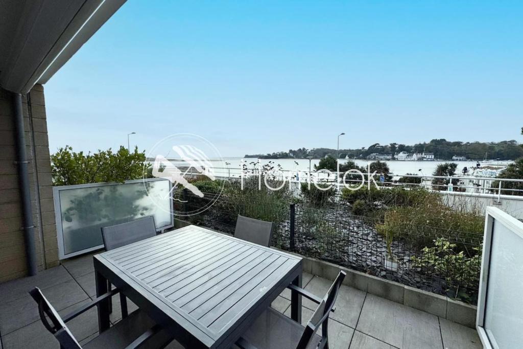 une table et des chaises sur un balcon avec vue sur l'eau dans l'établissement T3 de standing - Vue océan 180, à Guidel