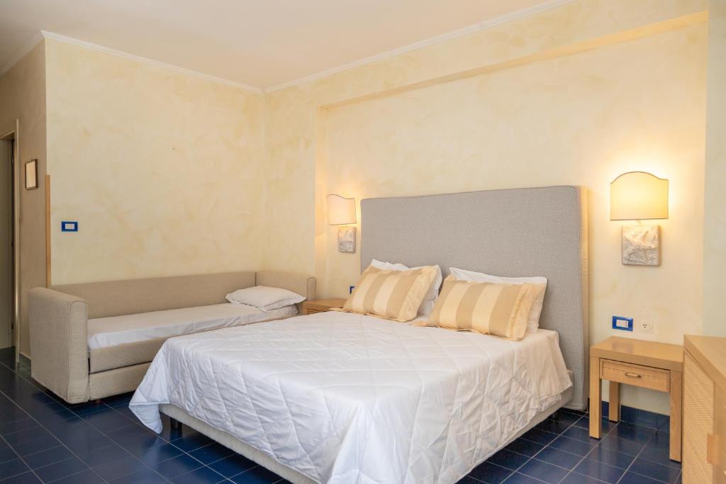 a bedroom with a large white bed and a couch at AH Premium Baia dei Faraglioni in Mattinata