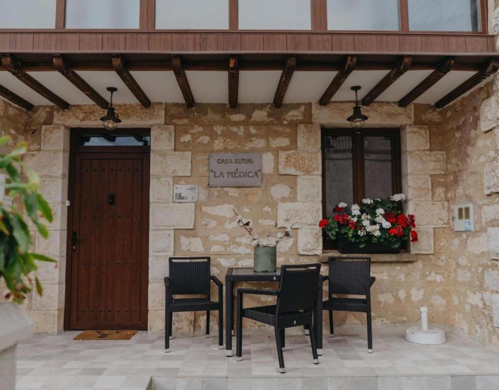 a patio with a table and chairs in front of a stone wall at Casa Rural La Medica in Sargentes de la Lora