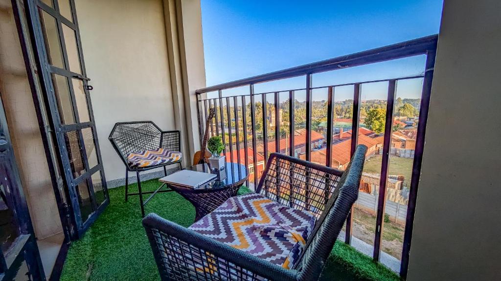 a balcony with two chairs and a table with a laptop at MAHALI MZURI Eldoret in Eldoret