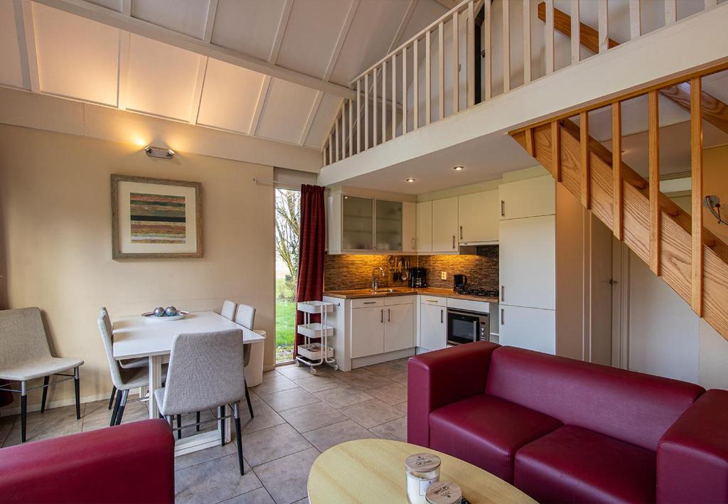 a living room with a red couch and a table at Bungalowpark Simpelveld - Delta 118 in Simpelveld