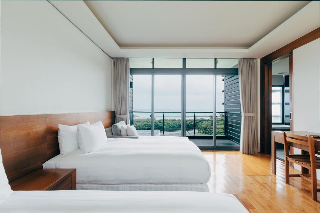 two beds in a hotel room with a large window at Adagio Shihtiping in Fengbin