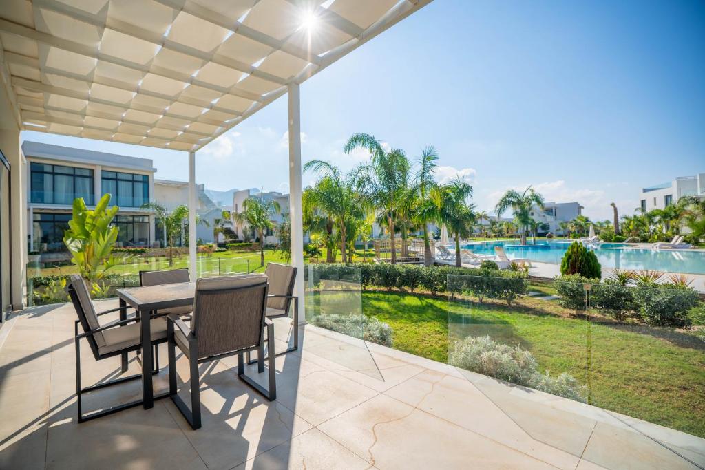 a patio with a table and chairs and a view of a pool at Beautiful and bright 2-bedroom apartment in Ayios Nikolaos