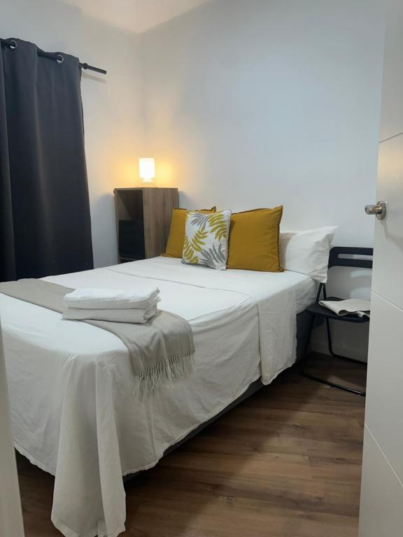 Una cama con sábanas blancas y almohadas amarillas. en Oporto 26, en Madrid