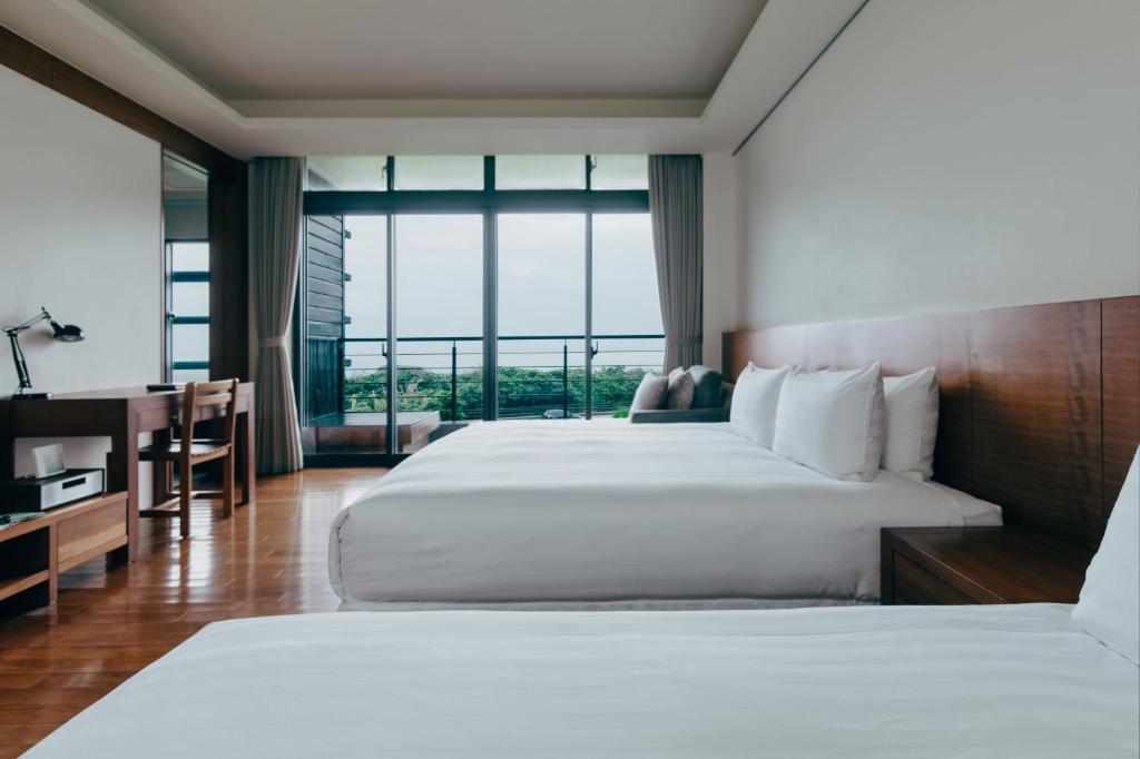 a bedroom with a large white bed and a desk at Adagio Shihtiping in Fengbin