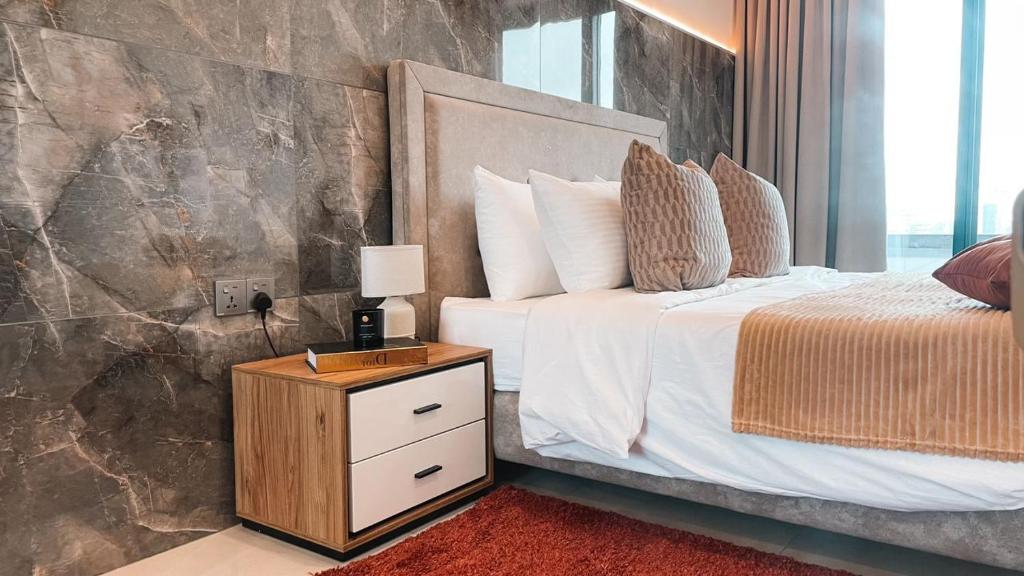 a bedroom with a bed and a night stand with a lamp at Sky Suites-KASS Towers in Okponglo