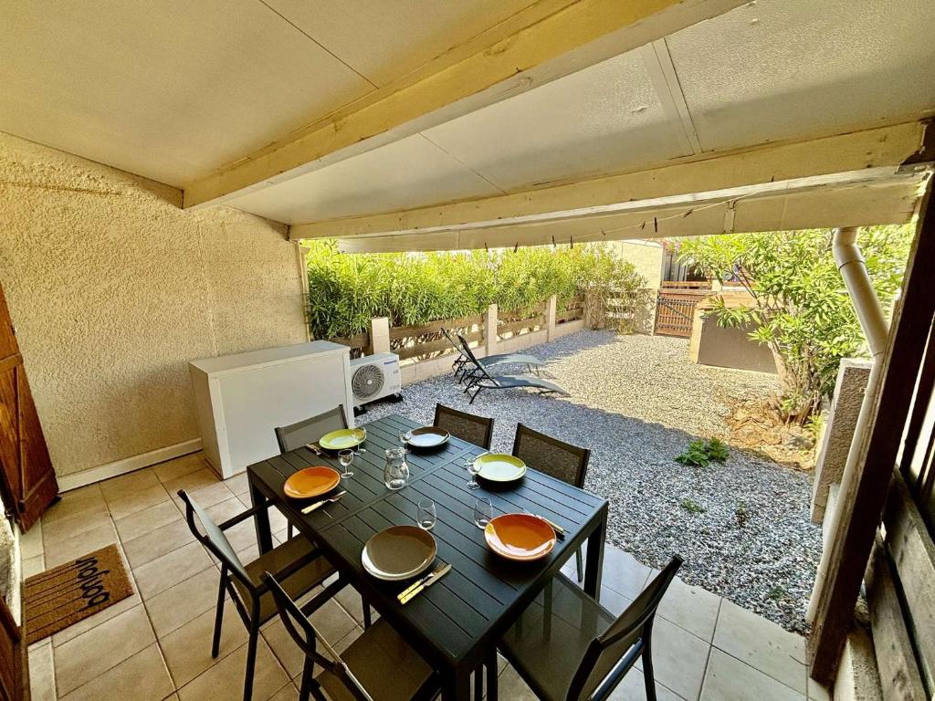 Une table à manger et des chaises sont disponibles sur la terrasse. dans l'établissement PN200-024 Maison 3 pièces - 4 couchages PORT LA NOUVELLE, à Port-la-Nouvelle