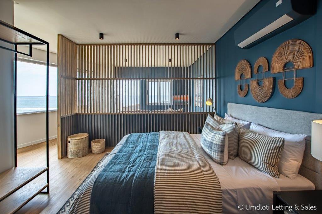a bedroom with a large bed with blue walls at High Tide at Umdloti Resort in Umdloti