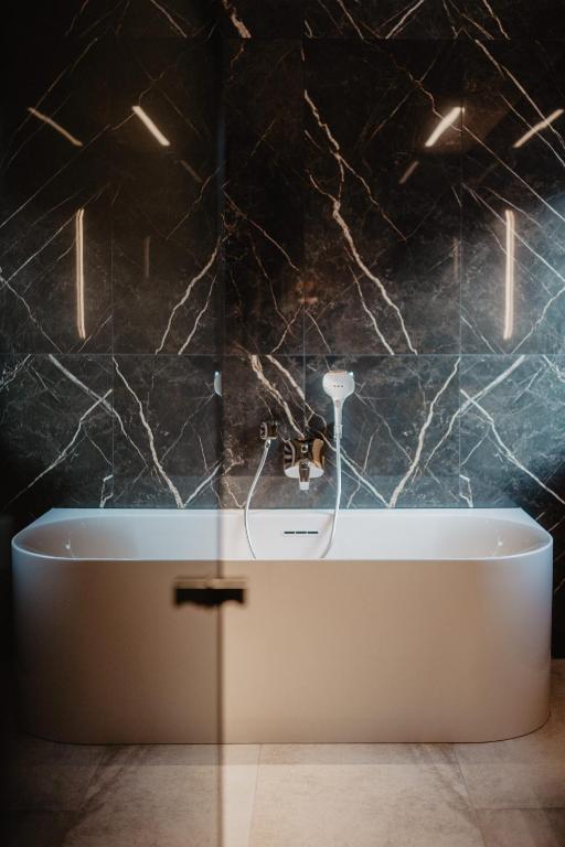 a bath tub in a bathroom with black marble walls at Hotel Berghof - St Johann in Salzburg in Sankt Johann im Pongau