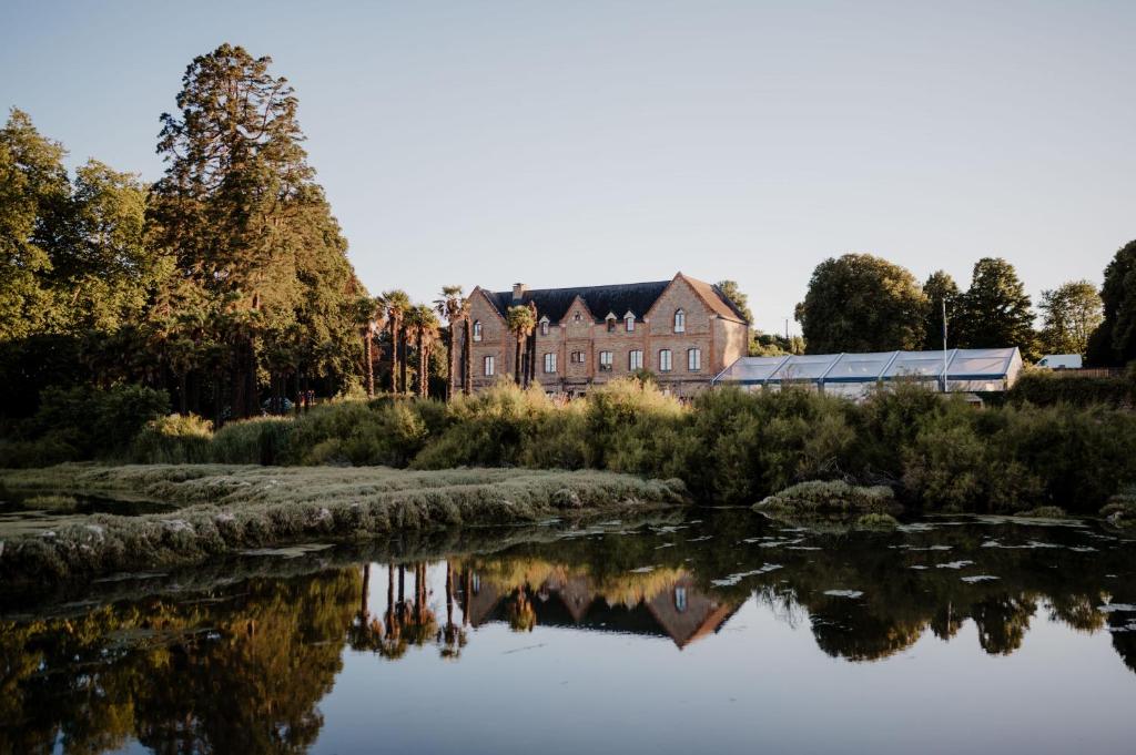 une ancienne maison reflétée dans l'eau d'un lac dans l'établissement Manoir du Plessis Kaër, à Crach
