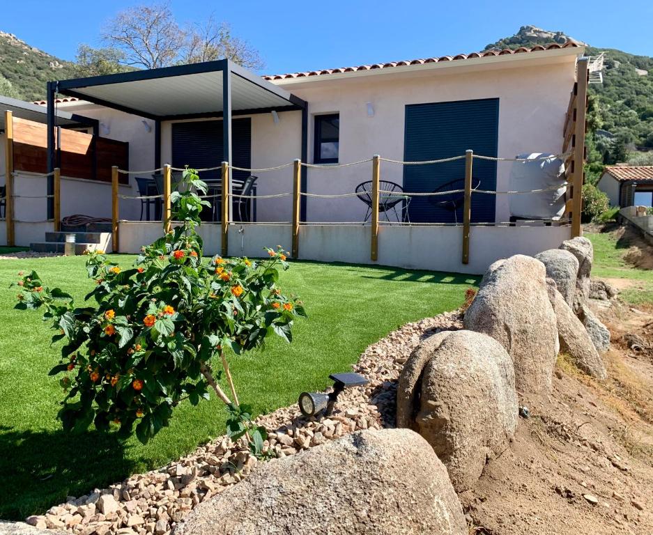 une maison avec un arbre dans une cour avec des rochers dans l'établissement Villa des Chênes, à Figari