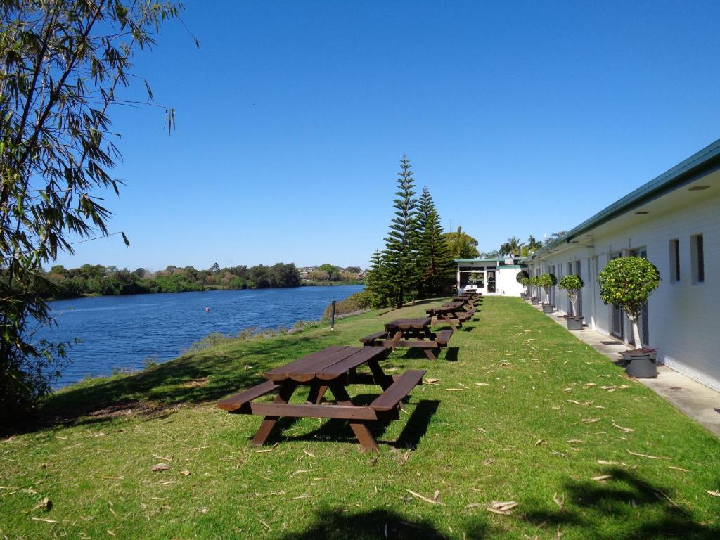 a row of picnic tables sitting next to a river at Moon River Motor Inn in Kempsey