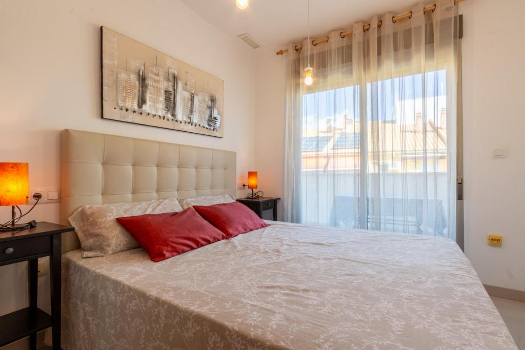 Un dormitorio con una cama grande con almohadas rojas. en Apartamento en El Campello, España, en El Campello
