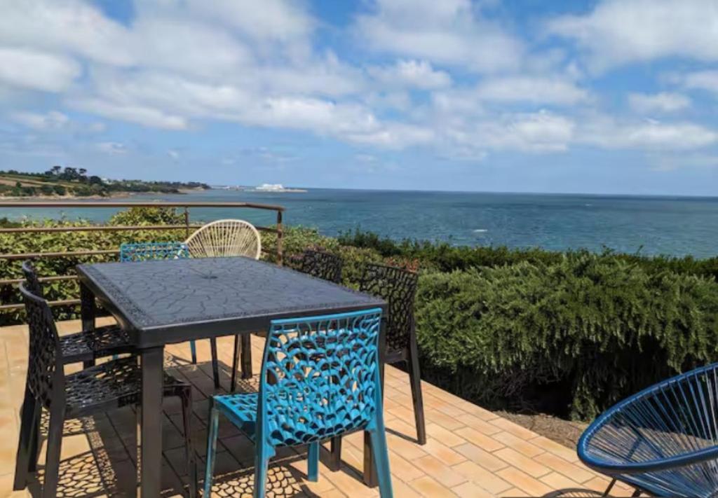 a table and chairs on a patio overlooking the ocean at La marée basse - vue mer imprenable in Saint-Pol-de-Léon