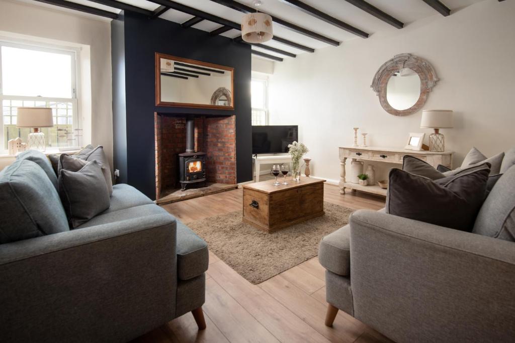 een woonkamer met twee banken en een open haard bij Hexham Cottage by Coast & Country Stays in Seahouses