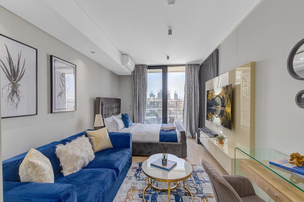 a living room with a blue couch and a bed at Bhonsane Executive Suite, Ellipse, Midrand in Midrand