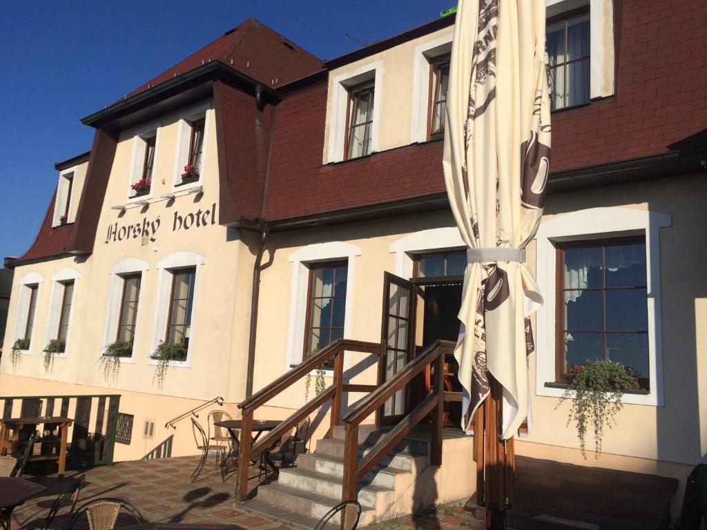 ein weißes Gebäude mit einem braunen Dach und einer Treppe in der Unterkunft Horský Hotel Kolowrat in Přimda