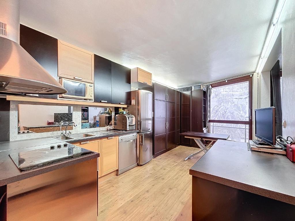 Una cocina con electrodomésticos de acero inoxidable y gabinetes de madera. en appartement Pied des Pistes à Villard de Lans Côte 2000 avec Ascenseur tout Equipée, en Prénatier