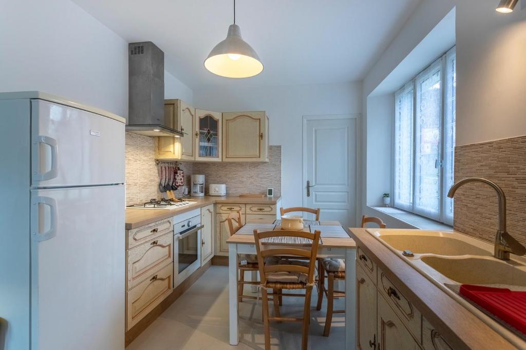 a kitchen with a white refrigerator and a table with chairs at Le Francvillois in Villefranche-Sur-Cher