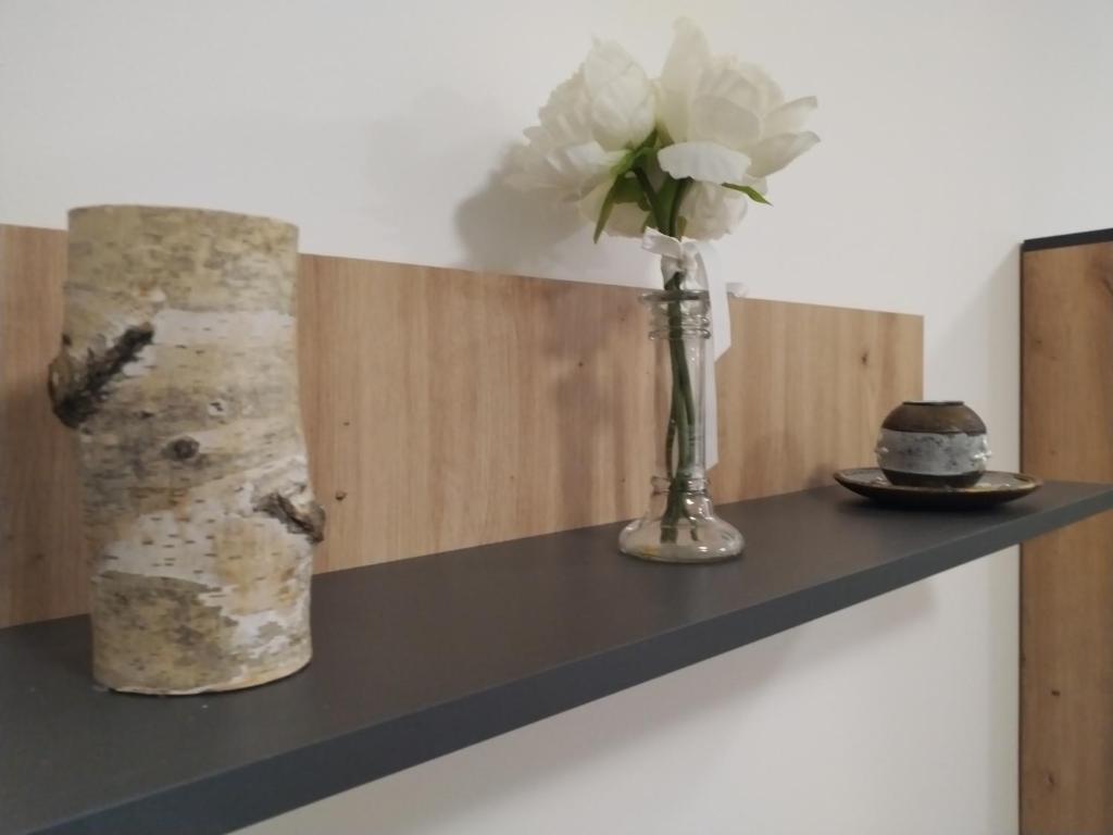 eine Vase Blumen auf einem Regal mit einem Kuchen in der Unterkunft Nina centar in Sombor