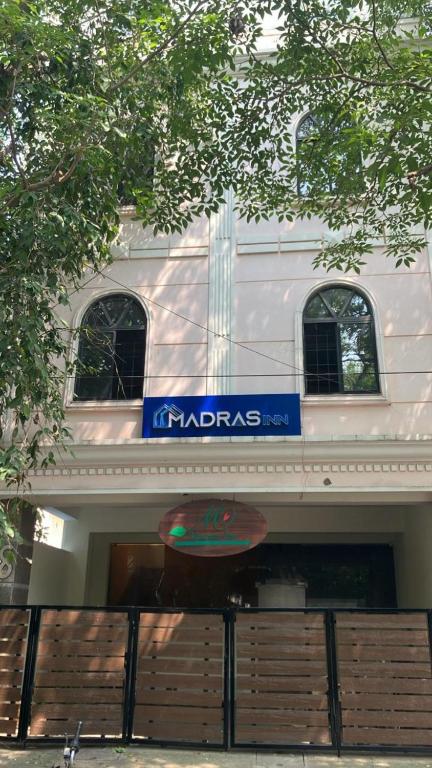 a white building with a blue sign on it at Madras Inn - Alwarpet in Chennai