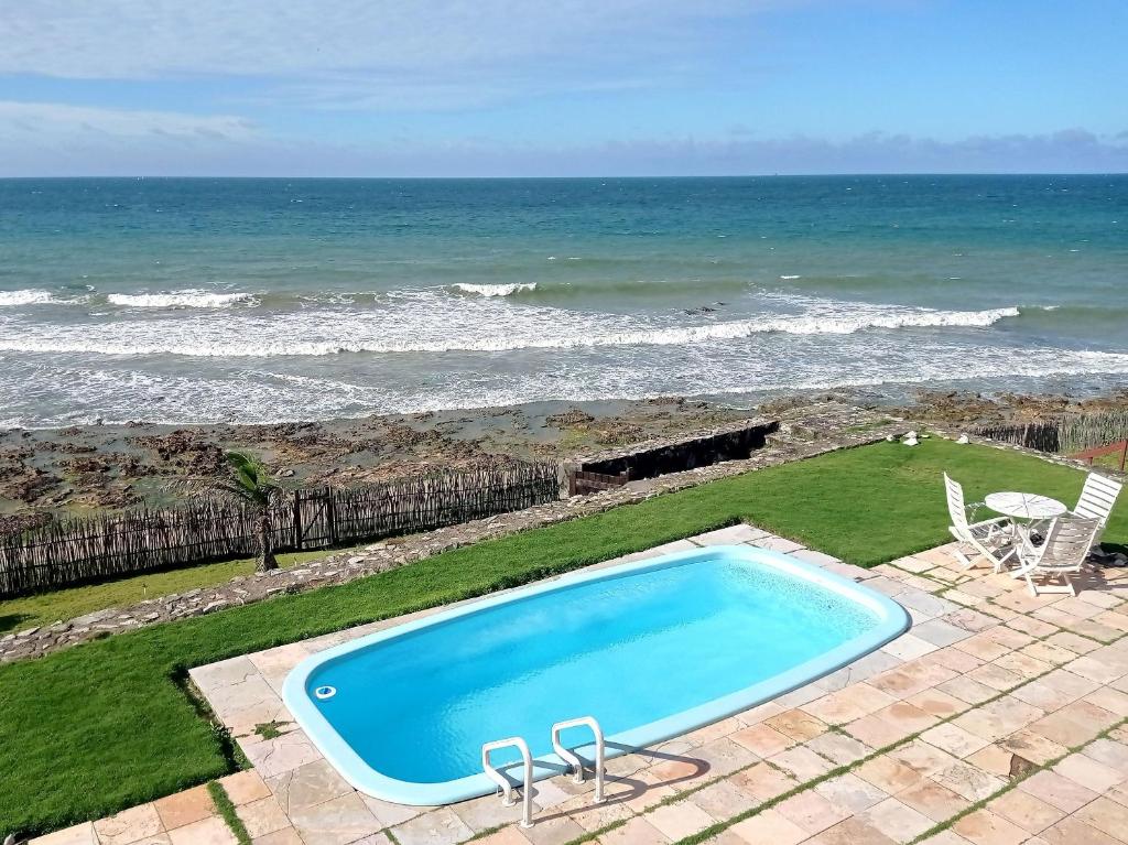 une piscine avec l'océan en arrière-plan dans l'établissement Casa Jangada - Incrível vista mar com Piscina e a melhor localização na Beira Mar da Taíba, à Taíba