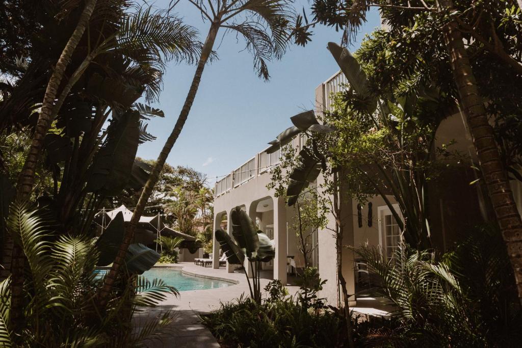 a house with a swimming pool and palm trees at Caza Beach Guesthouse in Durban