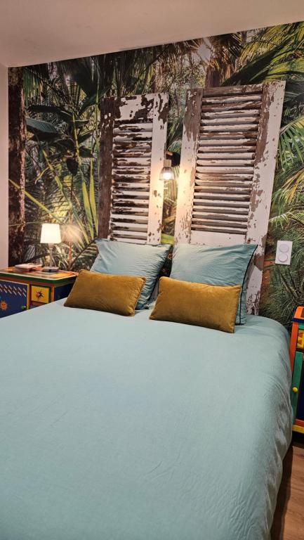 a bedroom with a large bed with blue pillows at Appartement au cœur de Marcillac-Vallon in Marcillac-Vallon