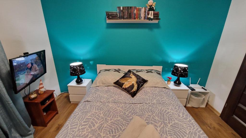 ein Schlafzimmer mit einem Bett mit einer blauen Wand in der Unterkunft Apartament Gwiazda przy Stoku na parterze z ogródkiem in Krynica-Zdrój