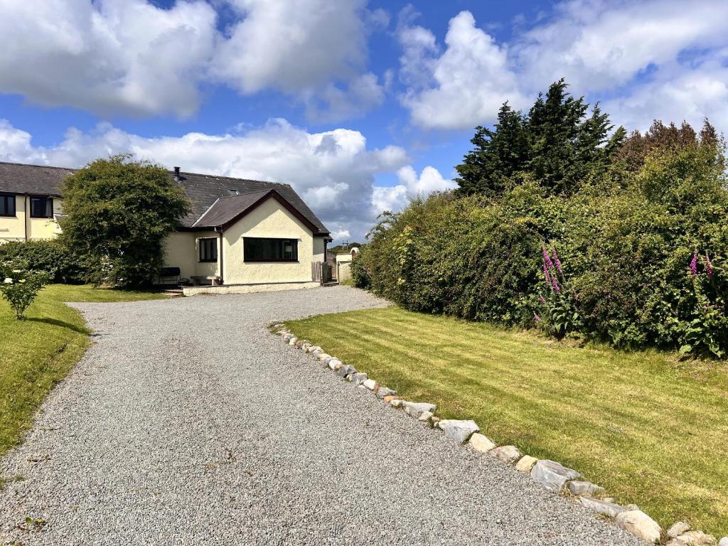 a house with a gravel road next to a yard at Detached 3 Bed Cottage Mountain Views- Pets Wifi in Beaumaris