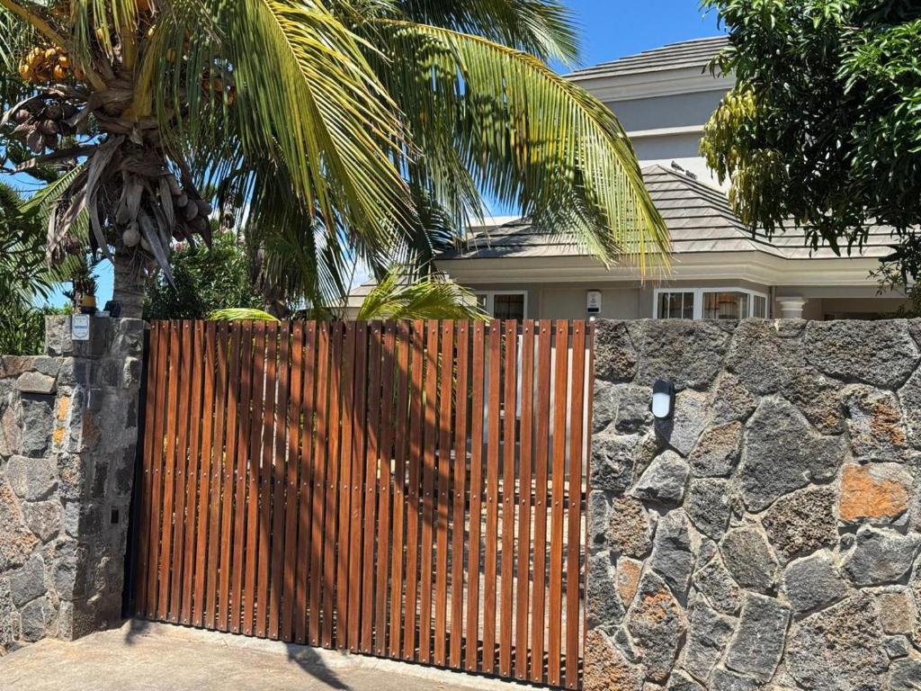 a fence in front of a house with a palm tree at Casa IVIA in Albion