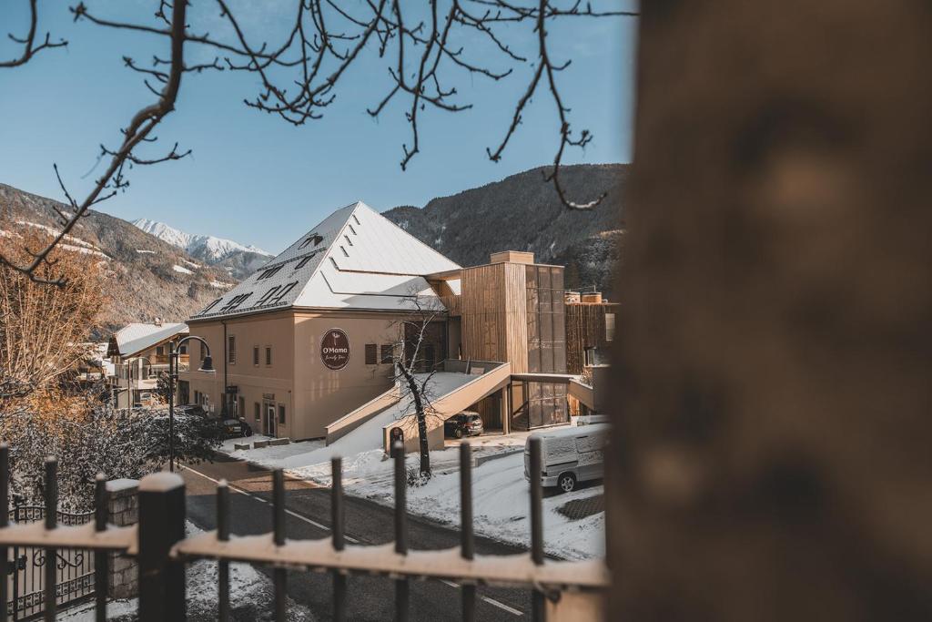 ein Gebäude mit Schnee auf dem Boden neben einem Zaun in der Unterkunft O'Mama family time - am Eggerhof in Mühlbach
