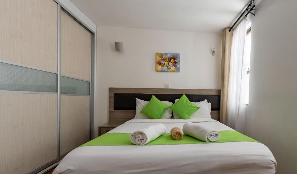 a bedroom with a large bed with green pillows at Erica Residences - Riverside in Nairobi