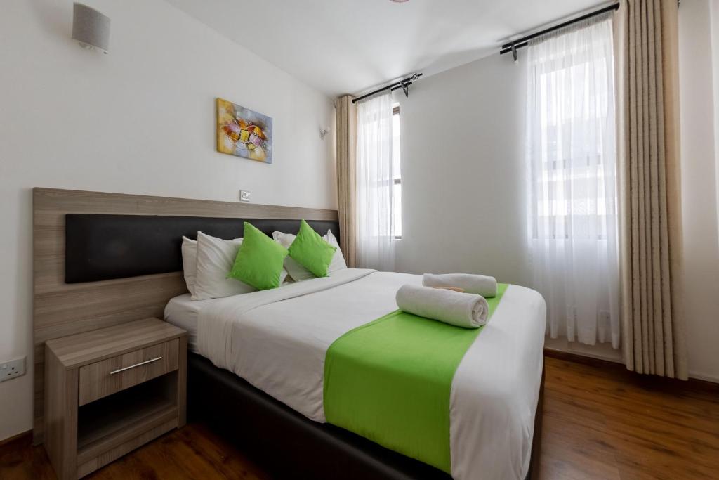 a bedroom with a large bed with green pillows at Erica Residences - Riverside in Nairobi