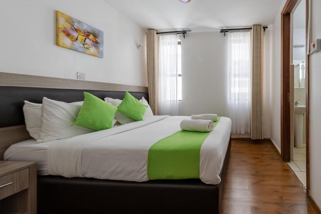 a bedroom with a large bed with green and white pillows at Erica Residences - Riverside in Nairobi